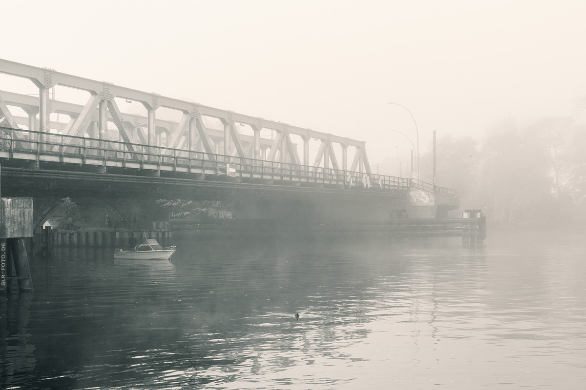 Angler unter Brücke im Nebel
